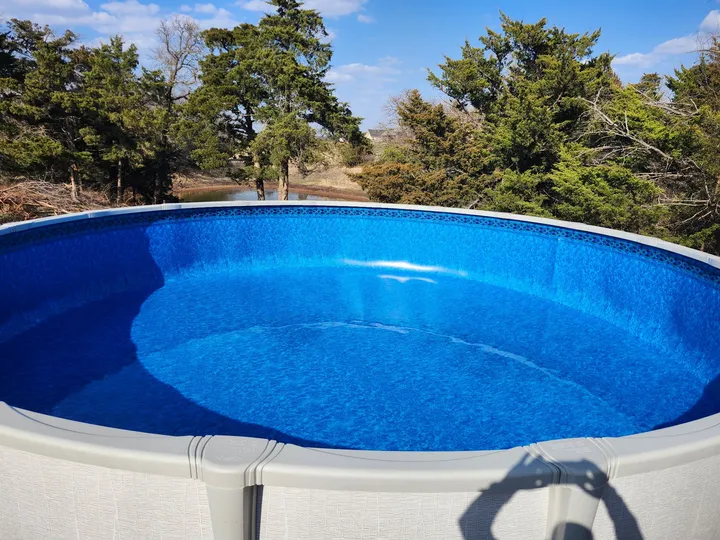 Above-ground pool with a new blue liner, filling with water