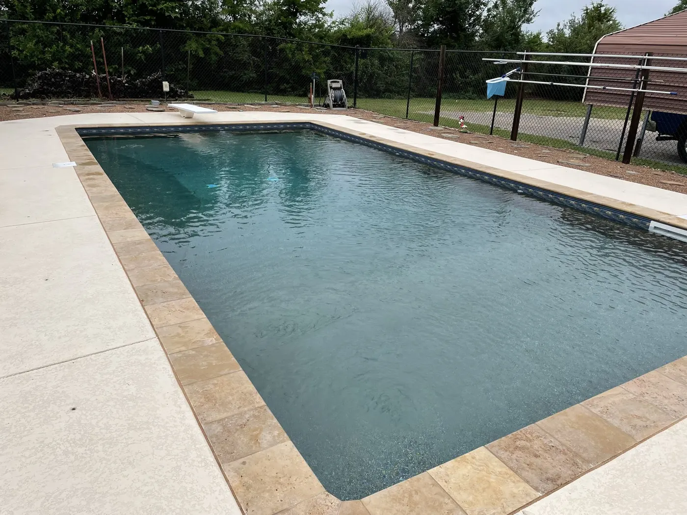 Same pool after renovation with travertine coping, coated deck, and new liner