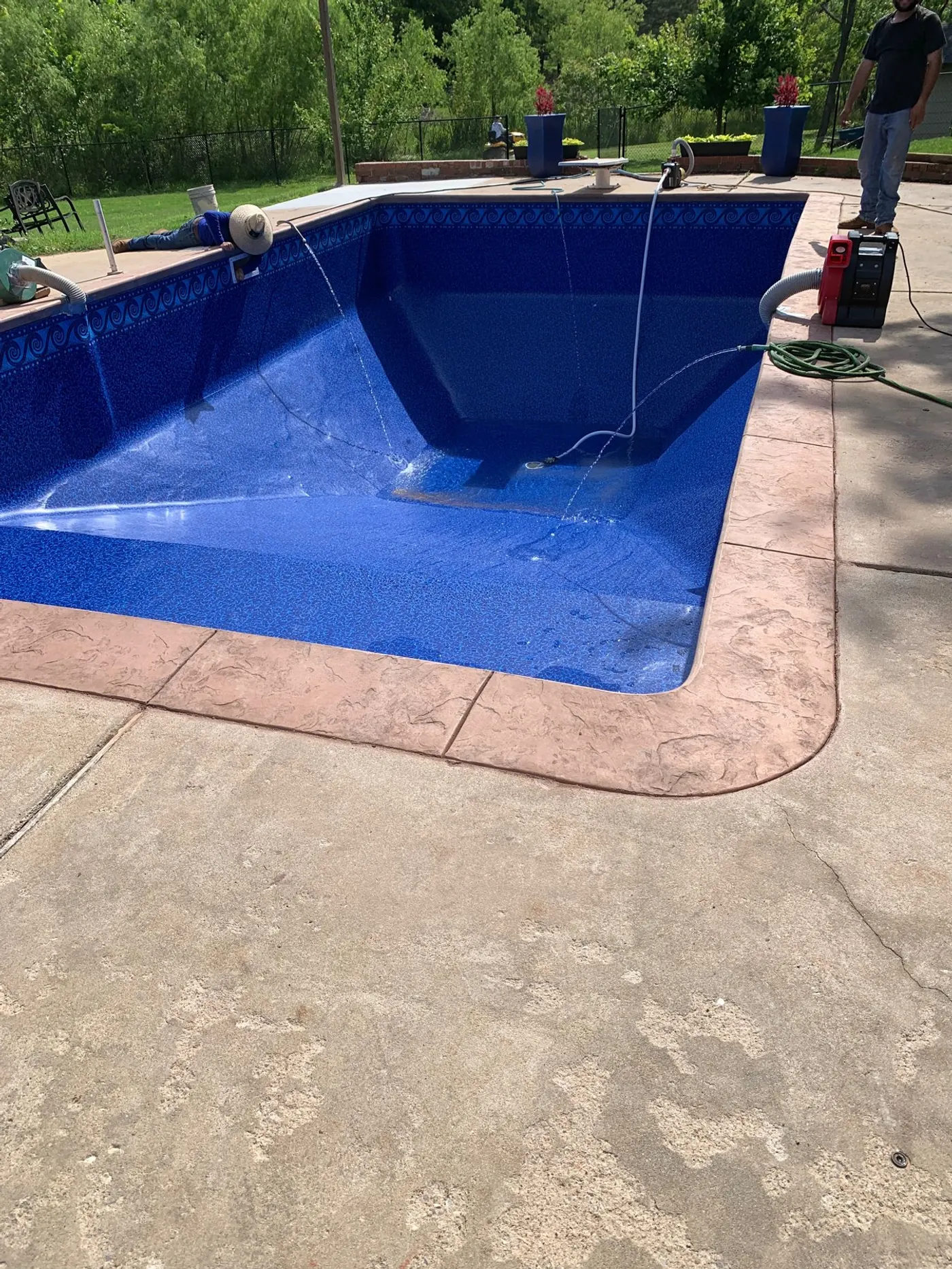 Same L-shaped pool after renovation with a new dark blue vinyl liner