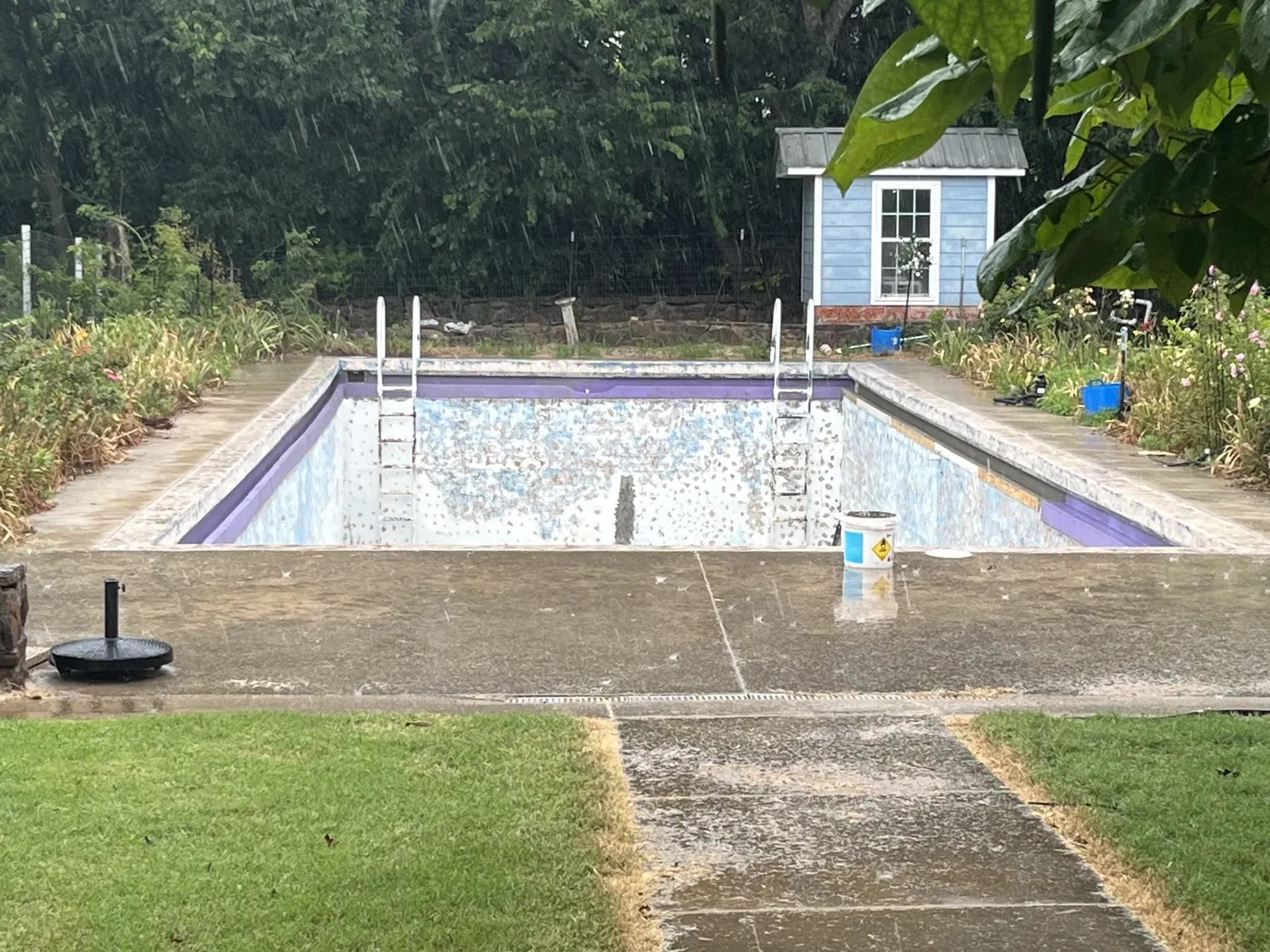 Century-old concrete pool with peeling paint and broken deck before renovation
