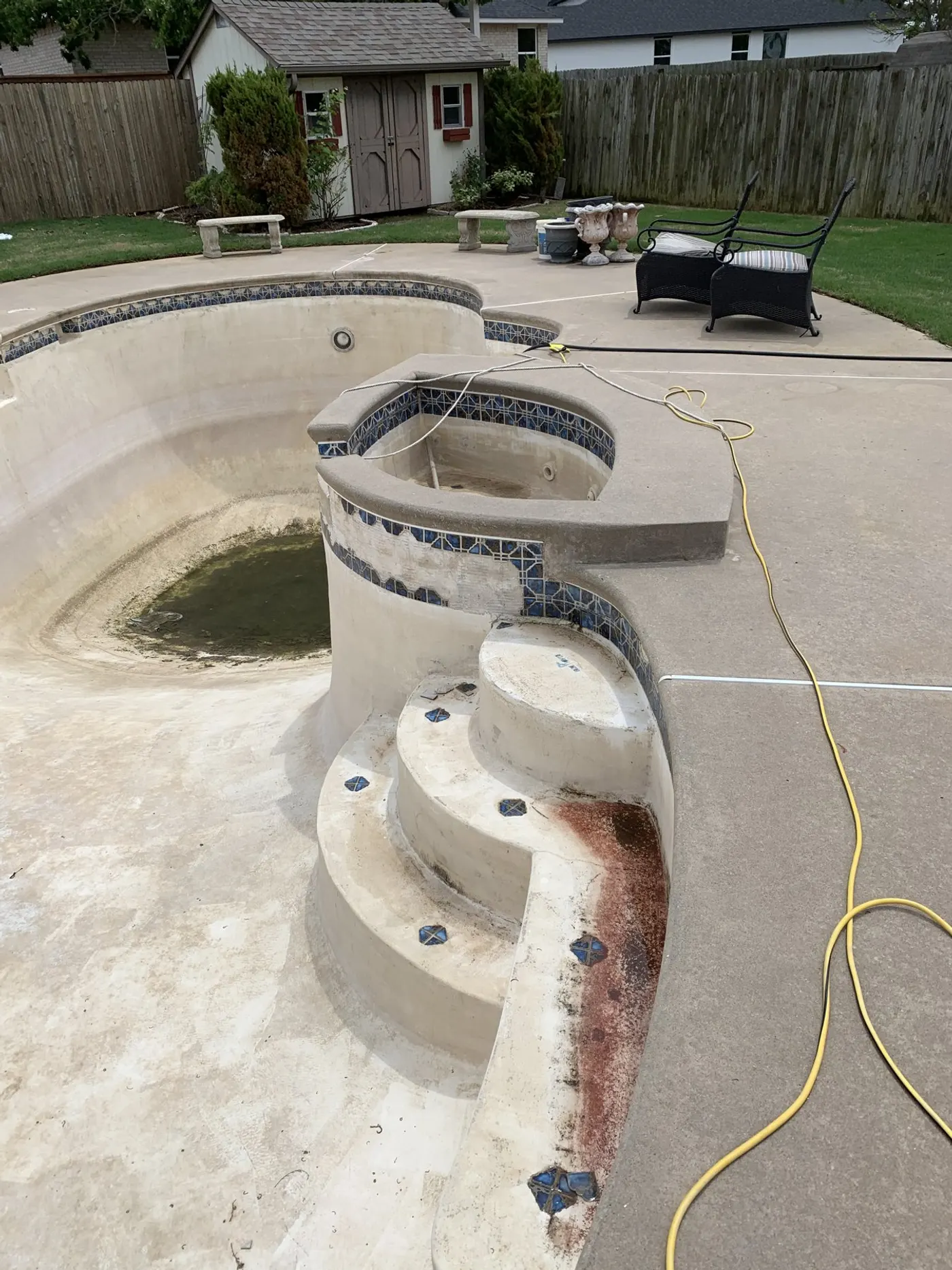 Concrete pool and raised spa with stained, worn plaster before resurfacing