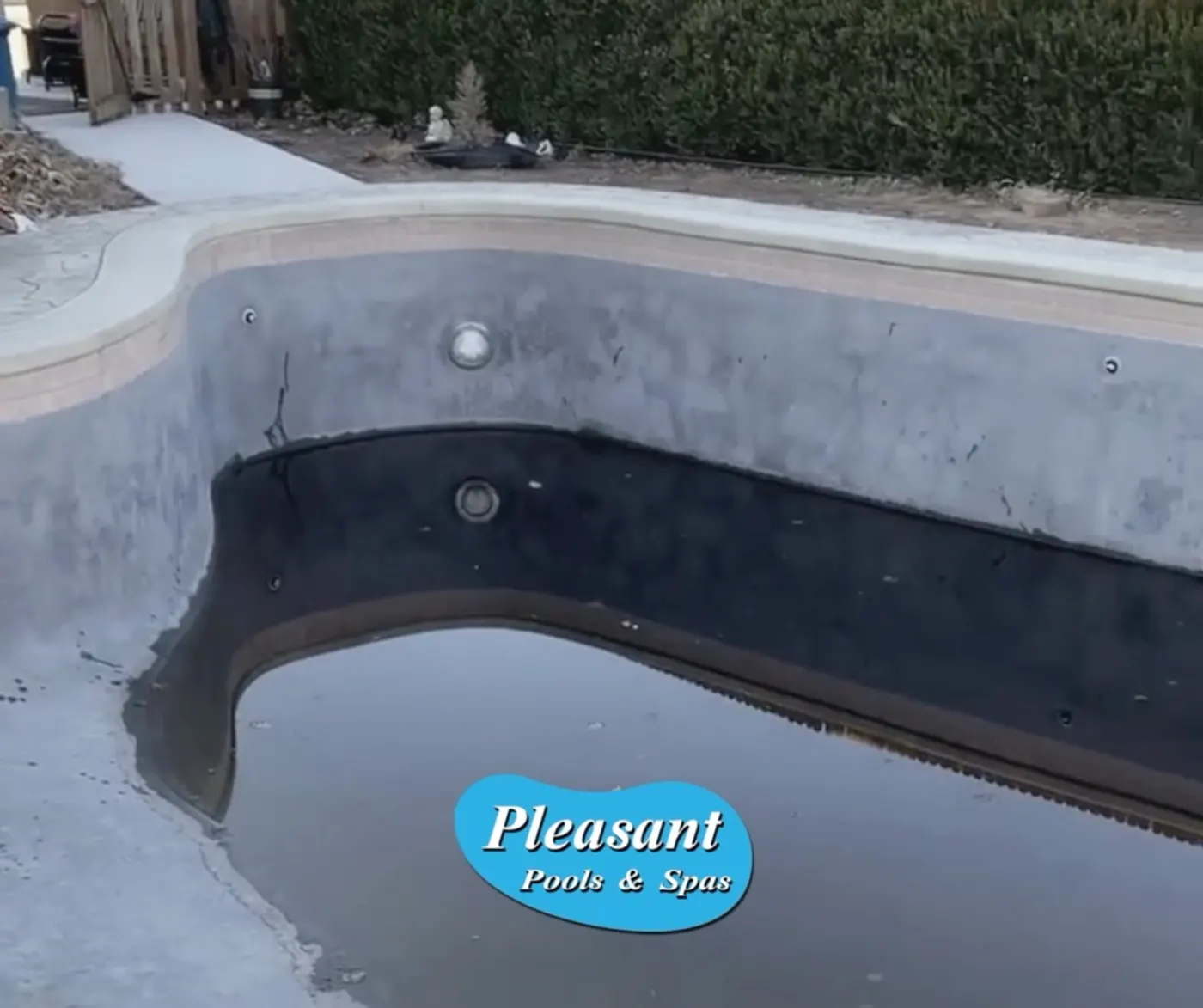 Drained pool with worn, stained plaster before renovation