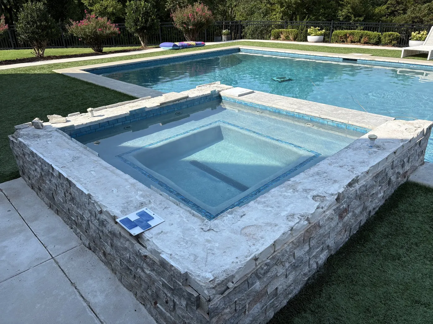 Raised concrete spa mid-renovation with coping removed and stone veneer going on