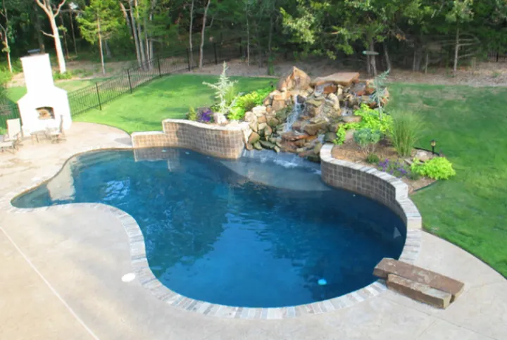 Freeform pool with stacked stone waterfall feature and extensive plantings