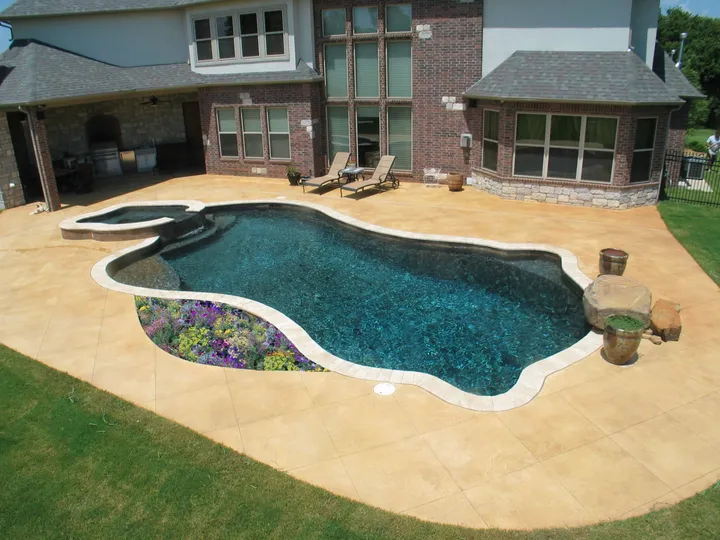 Large oval pool with integrated spa and purple flower landscaping accent