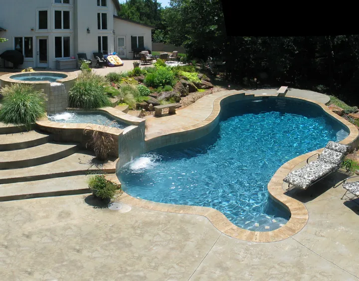 Curved pool with waterfall feature and stacked stone accents in residential setting