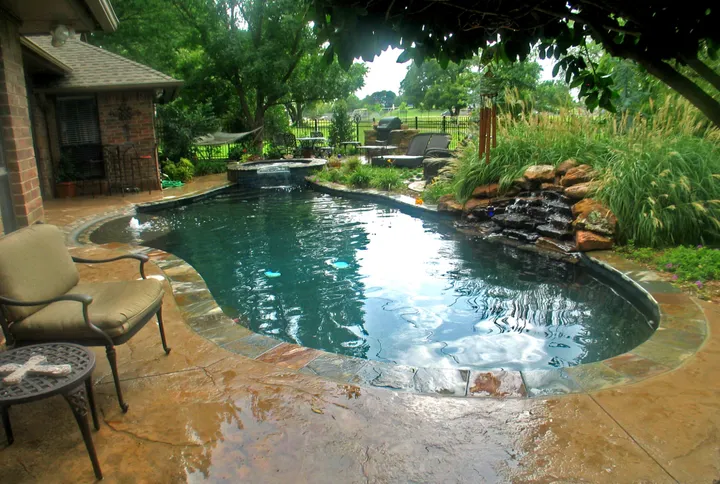 Kidney-shaped pool with waterfall feature and natural stone landscaping