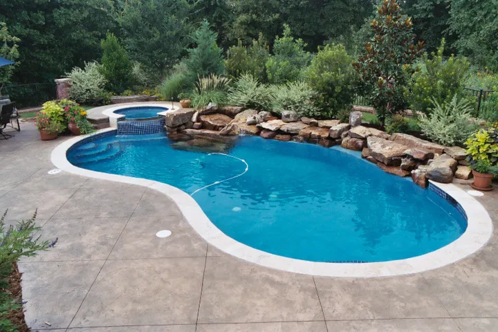 Large oval pool with integrated spa in rural open setting