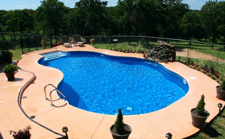 Large oval vinyl pool with simple landscape and integrated spa feature