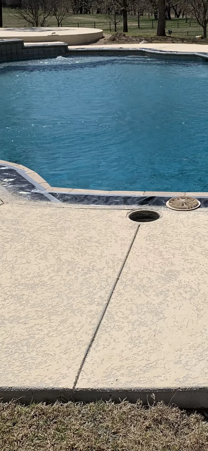 Coated pool deck meeting the waterline and coping
