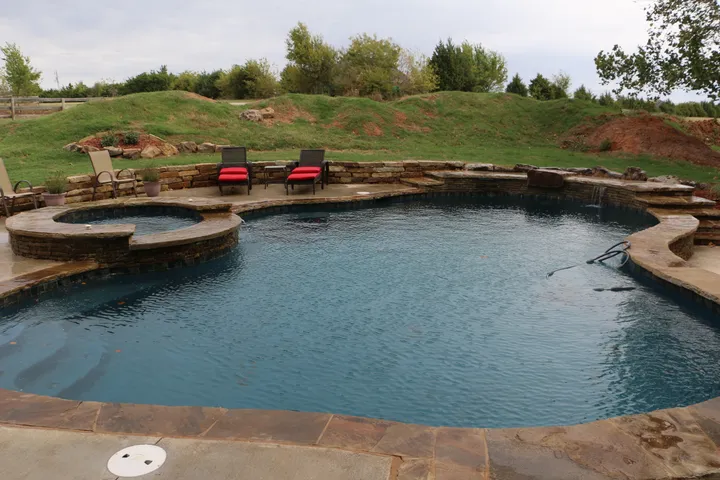 Freeform pool design with stone retaining walls and concrete decking, similar angle to IMG_1286