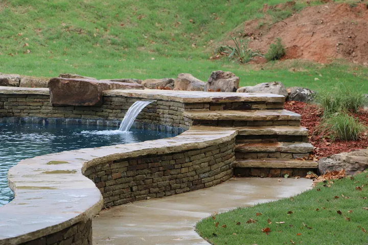Stone-lined freeform pool with cascading waterfall and natural landscaping