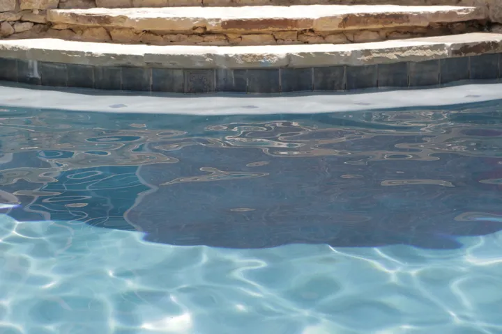 Freeform pool with curved lounge chairs and waterfall feature