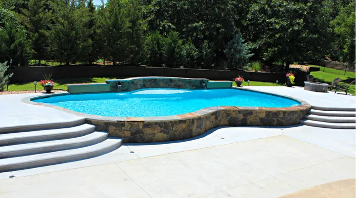 Large curved pool with rock features and spa in open landscape