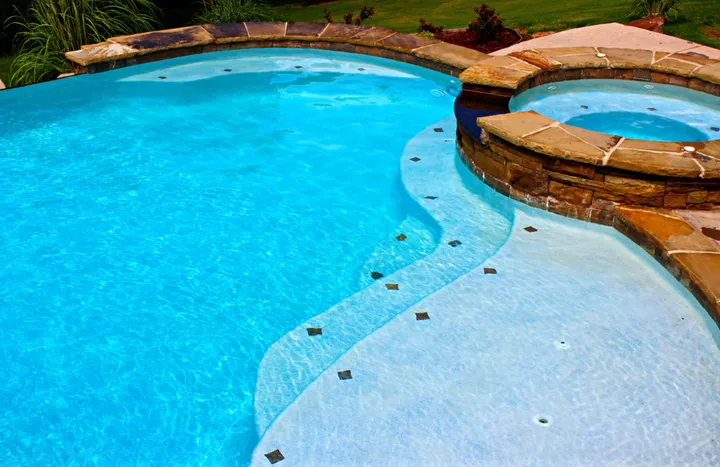 Curved pool with rock waterfall feature and integrated spa area