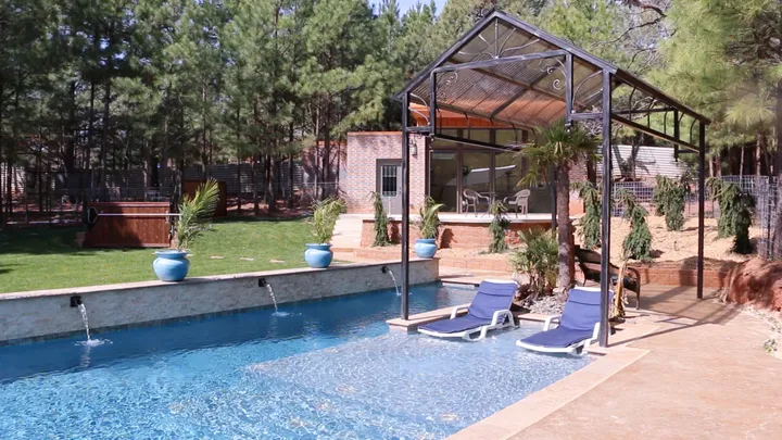 Wide shot showing entire modern pool setup with attached spa, deck, and pergola