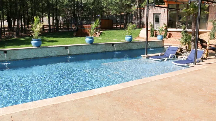 Contemporary rectangular pool with concrete coping and stone waterfall features
