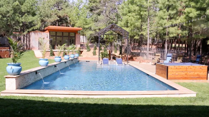 Rectangular pool with spa and modern stone architecture from angle showing full property