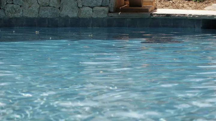Crystal clear pool water with stone surround showing excellent water quality