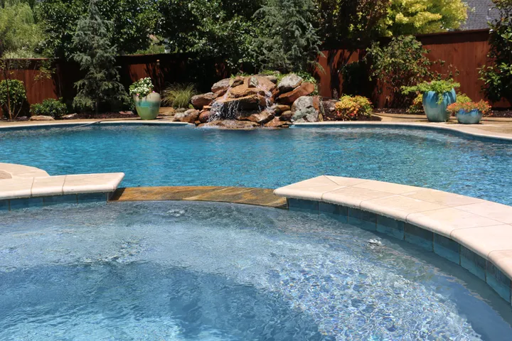Elegant completed pool with integrated spa and cascading rock waterfall feature