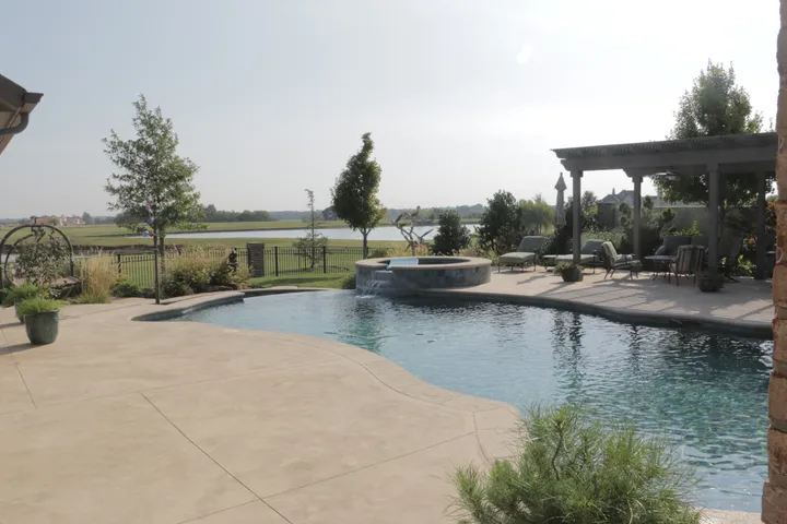 Large freeform pool with circular spa and pergola overlooking open landscape