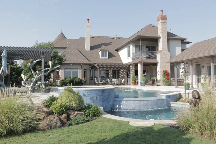 Luxury home with elaborate multi-level pool complex featuring spa and waterfall