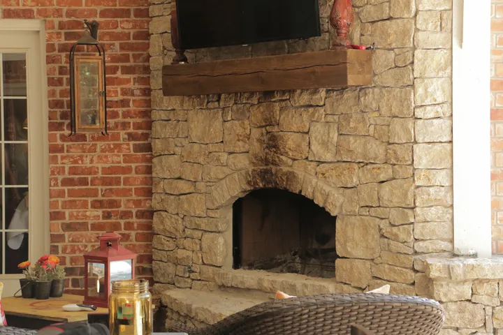Outdoor fireplace with stone surround on brick patio with furnishings