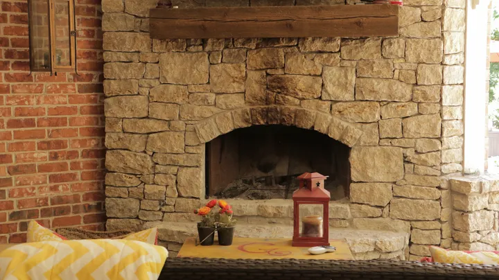 Stone fireplace with arched opening decorated with flowers and lantern