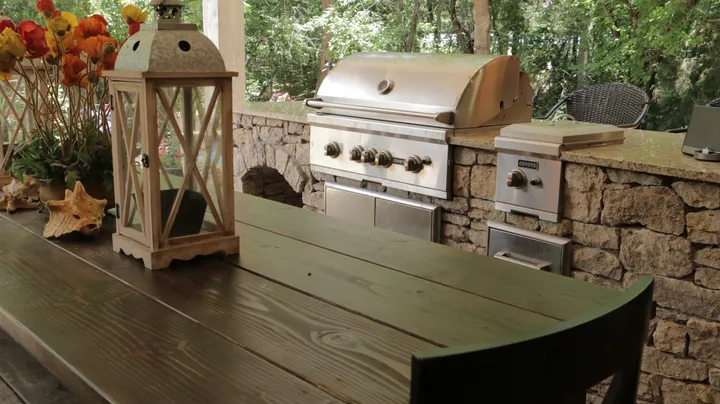 Outdoor kitchen counter with stainless steel grill and stone surround