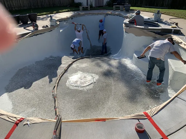 Pleasant Pools crew hand-troweling new plaster in a freeform pool