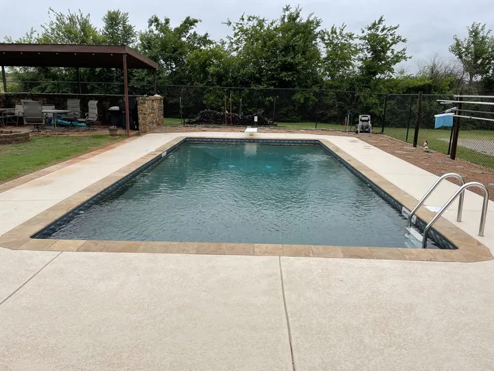 Renovated pool with new travertine coping, coated deck, and a backyard pavilion