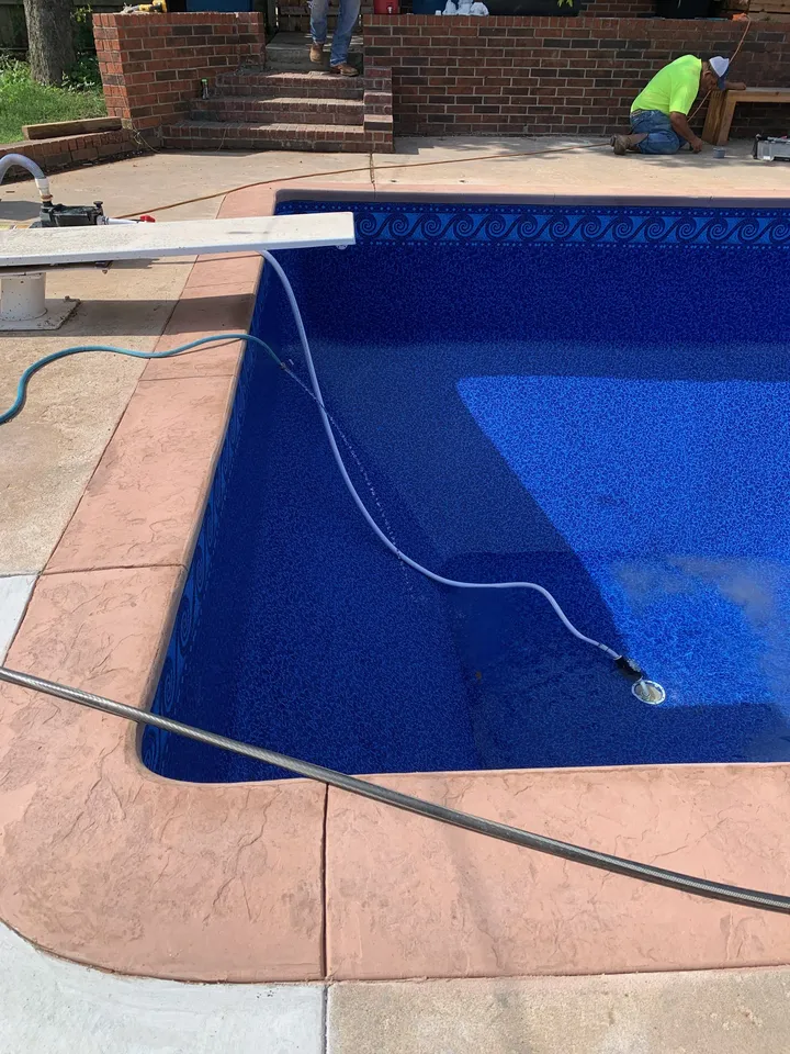 L-shaped pool with a new dark blue vinyl liner and terracotta-colored deck