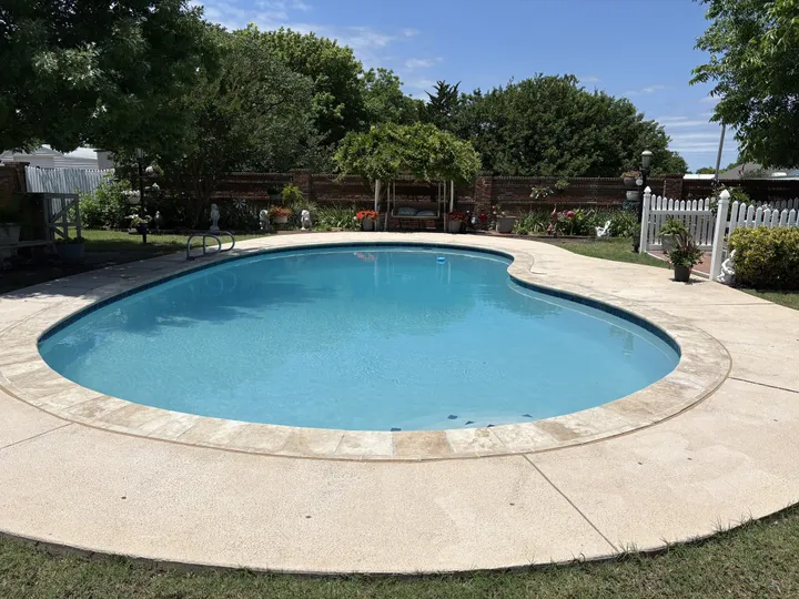 Kidney-shaped pool with new travertine coping and fresh plaster