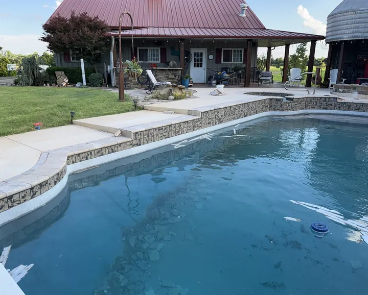 Renovated pool with new tile and a stacked-stone raised wall