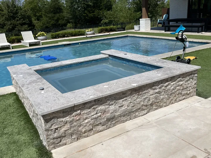 Raised spa finished with stacked-stone veneer and travertine coping