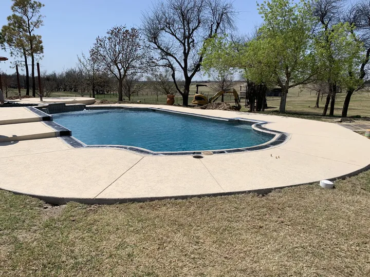 Freshly coated pool deck with dark coping, wide backyard view