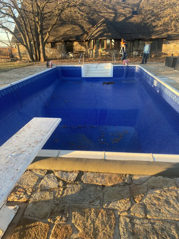 Vinyl pool with a new blue liner and diving board after renovation