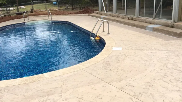 Renovated vinyl pool with travertine coping and a stamped concrete deck