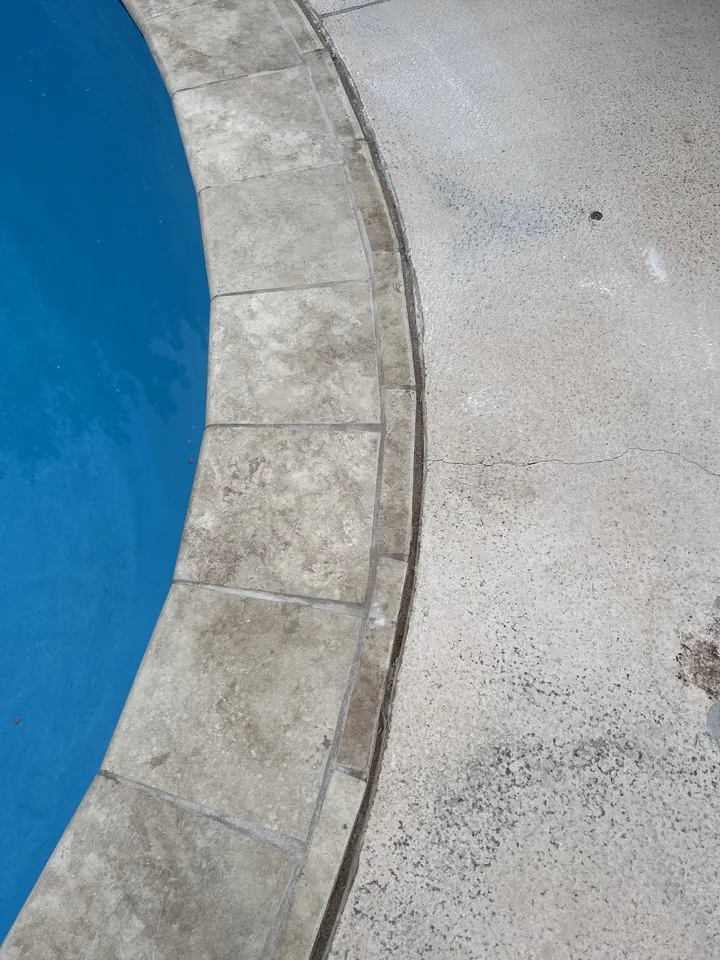 Close-up of new travertine coping against fresh blue plaster