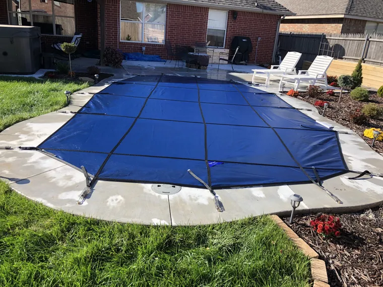 Blue safety cover custom-cut to a lagoon-shaped pool
