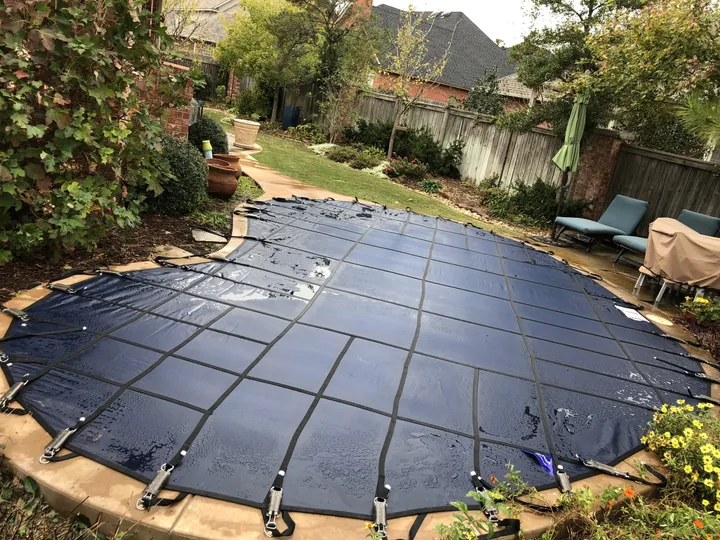 Mesh safety cover on a freeform pool surrounded by gardens