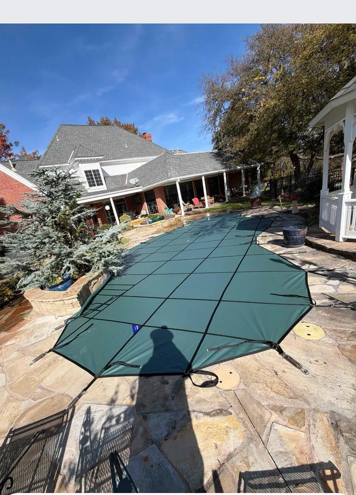 Green safety cover on a freeform pool with a flagstone deck