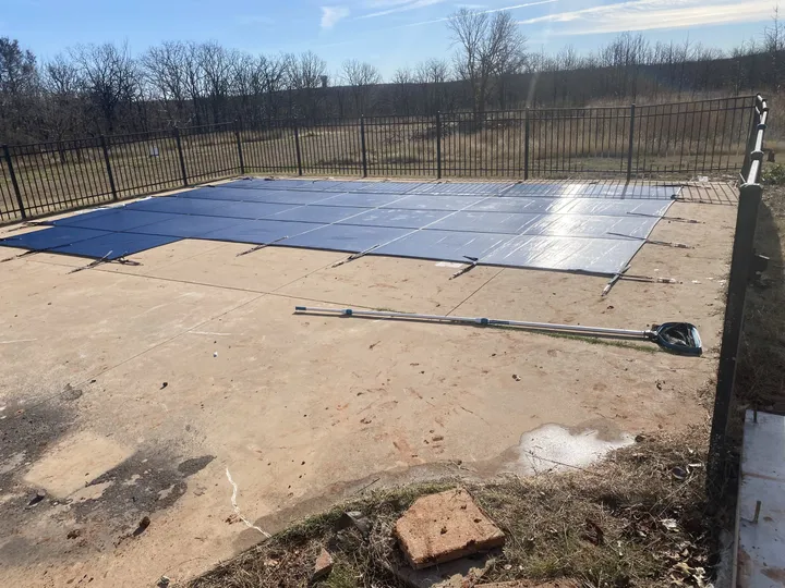Safety cover installed for winter on a fenced backyard pool