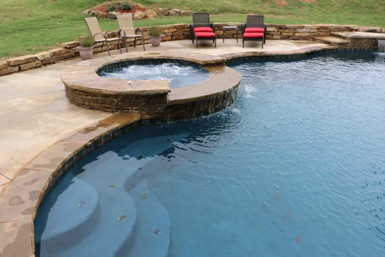 Circular hot tub integrated with rectangular pool, outdoor seating and landscaping