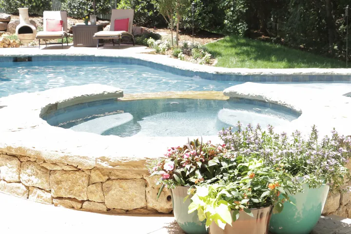 Spa with stone surround and colorful planters in pool complex