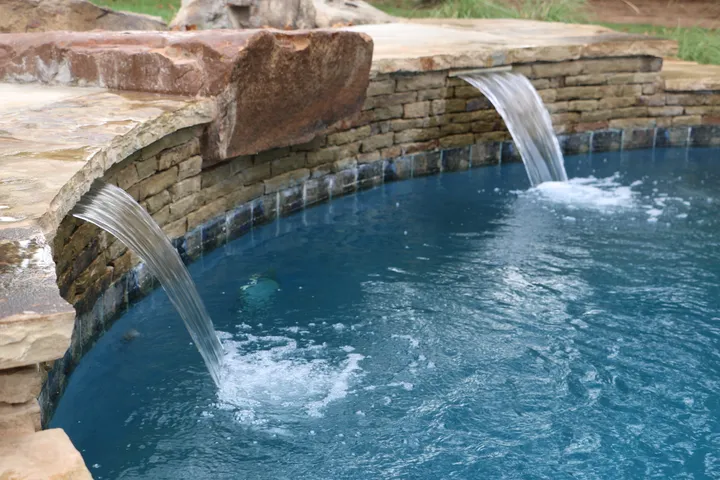 Detailed sheet waterfall flowing over stone ledge with pool below