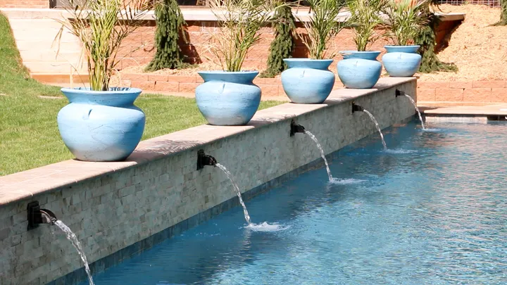 Decorative water fountains with white stone coping and blue painted pots