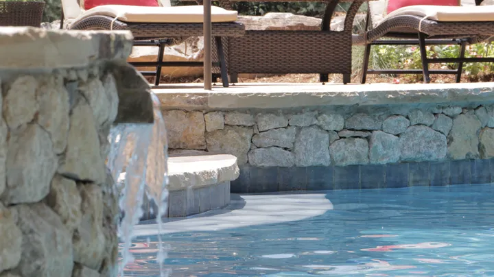 Stone waterfall feature with architectural stonework and pool integration