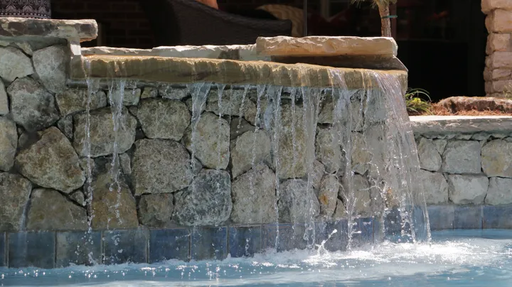Tiered stone waterfall feature with multiple water streams