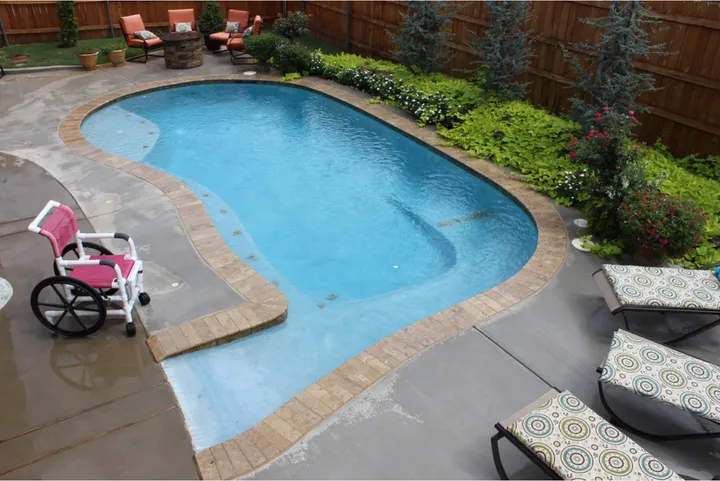 Pool with cascading waterfall feature and stone wall in backyard
